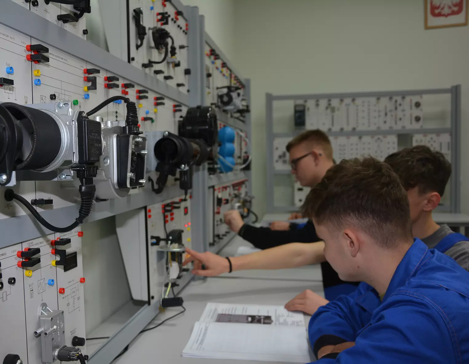 Uczniowie kierunku Technik Mechanizacji Rolnictwa i Agrotroniki siedzą przed szafą elektryczną